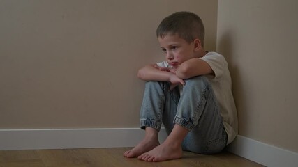 Boy sits on floor in isolation, arms wrapped tightly around knees. Child posture reflects quiet emotion and deep sadness. Thinking remains visible in still child form as emotion stays silent.