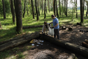People picking up litter in the woods, active environmental volunteers working in forest clearing, collecting plastic and waste to keep nature clean, environmental responsibility and teamwork outdoors