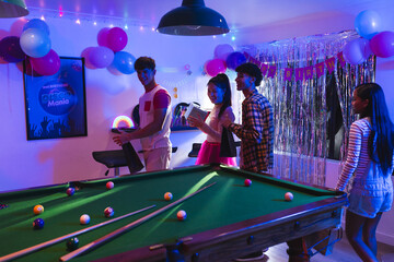 Naklejka premium Teenagers enjoying birthday party with pool table and colorful decorations indoors