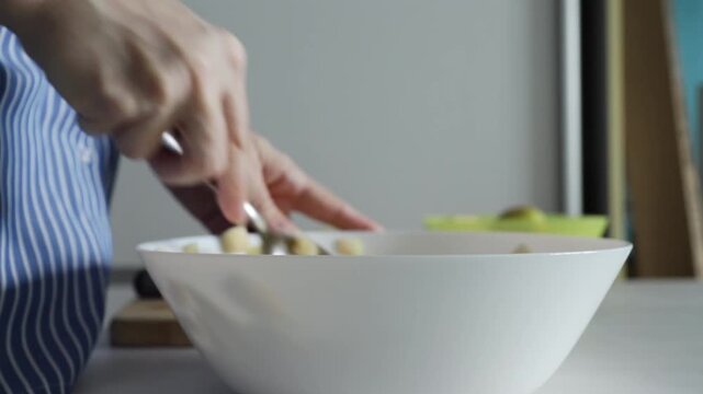 Hands mixing apple pieces in bowl, close up of homemade cooking process, preparation of fresh fruit for pie, strudel, or compote.