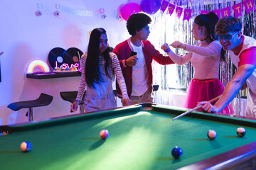 Naklejka premium Teenagers playing pool and celebrating birthday in colorful party room