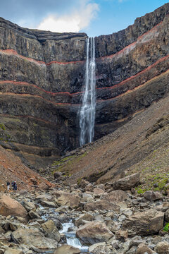 Cascade de Hengifoss, devant une paroi stri&eacute;e de rouge et de noir, au fond d'un petit canyon,  dans l'est de l'Islande