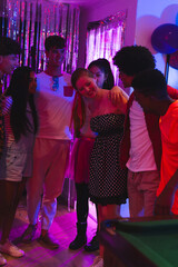 Teen friends celebrating together at home, enjoying party with colorful lights