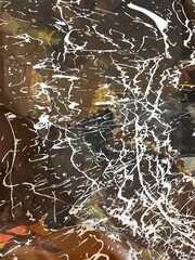 Abstract background of dynamic paint splatters and stains in earthy tones of ochre and brown, contrasted with bold black and white splashes.