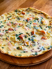 Frittata - scrambled eggs with roasted salmon bites, fried onion and fresh thyme on wooden table	