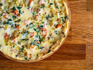 Frittata - scrambled eggs with roasted salmon bites, fried onion and fresh thyme on wooden table	