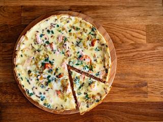Frittata - scrambled eggs with roasted salmon bites, fried onion and fresh thyme on wooden table	