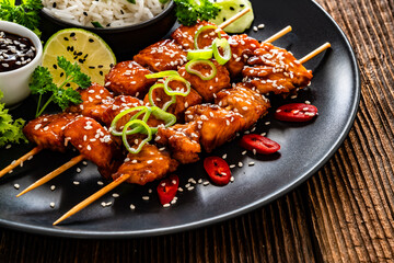 Fried teriyaki salmon skewers with white rice on wooden table