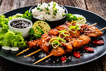 Fried teriyaki salmon skewers with white rice on wooden table