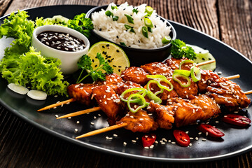 Fried teriyaki salmon skewers with white rice on wooden table