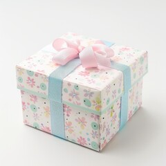 A square gift box with a pastel floral design, adorned with a pale pink bow and light blue ribbon, sits on a white background