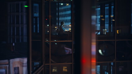 Manager silhouette sitting desk talking night building visible through windows © stockbusters