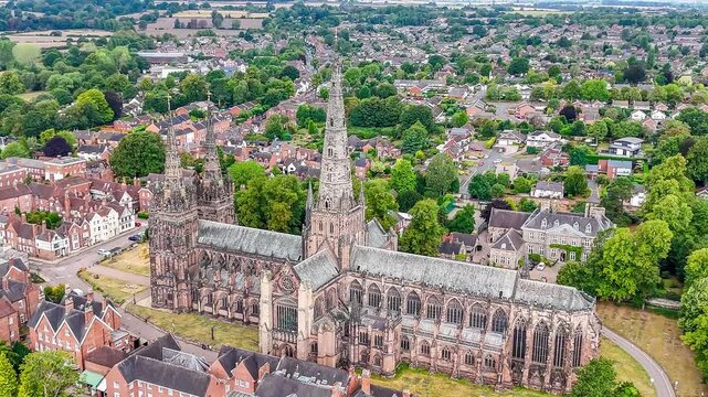 A receding aerial view followed by a rotating view the cathedral in the town of Lichfield, UK in summertime