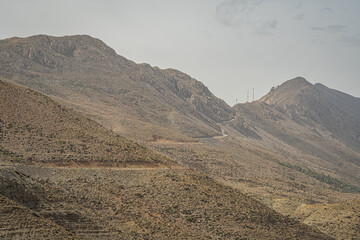 Remote Moroccan hills with steep rocky slopes and narrow road cutting across the rugged dry landscape