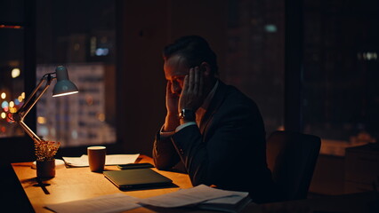 Overworked businessman sitting night office closeup. Weary man massaging neck