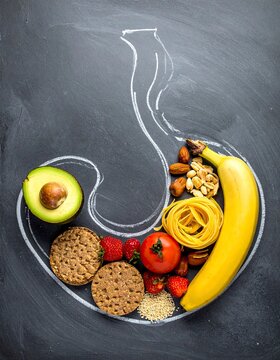 Naklejki  human stomach drawn in white chalk on a dark gray chalkboard background. Inside the chalk outline, a variety of healthy foods are arranged to fill the shape of the stomach. 