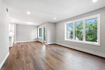 Large, empty living room with a wooden floor and white walls