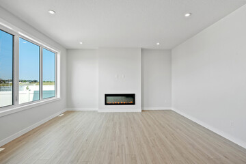 Large, empty living room with a fireplace and a window