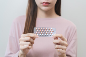 Contraception and pregnancy, menstruation concept, birth control pills asian young woman hand holding hormonal oral contraceptive medicine, take pharmaceutical to prevention, safe virus sex disease.