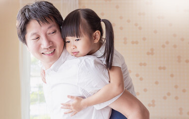 Portrait of smile father giving his young daughter a piggyback ride indoors, Warm and joyful family bonding moment at home. Father’s day