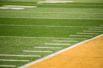 Obraz premium Football field green artificial turf with white lines and hash marks yellow out of bounds