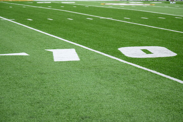 Football field green artificial turf with white lines and hash marks	