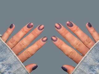 Young woman’s hand with smooth skin and stylish, modern, hand-painted nail art manicure on a soft...