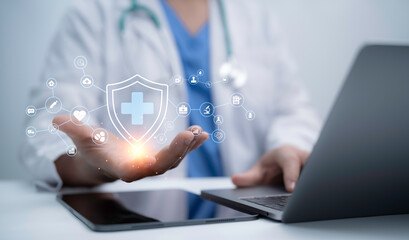 Doctor using laptop and tablet with digital healthcare security shield, medical icons, cloud service and innovation technology concept for telemedicine, data protection and modern patient care