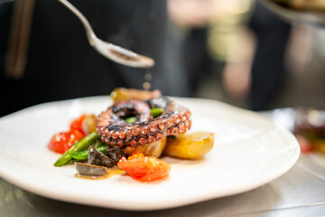Gourmet octopus dish served with roasted potatoes, cherry tomatoes, green beans, and sauce drizzle. Fine dining plating with vibrant colors and elegant presentation
