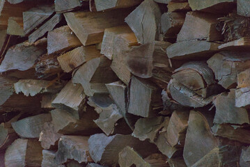 A dense wall of stacked firewood in natural shades of brown and gray, creating a rich, rustic texture and pattern perfect for backgrounds and cozy themes.