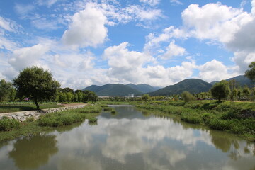 파란 하늘과 흰구름 그리고 강에 비친 나무들의 모습