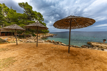 Tara Beach on the island of Rab, Straw sun umbrellas on the shore of the Adriatic Sea,