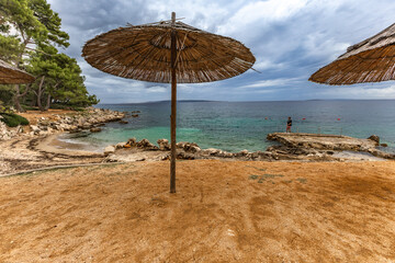 Tara Beach on the island of Rab, Straw sun umbrellas on the shore of the Adriatic Sea,