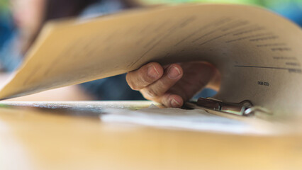 Close up to woman finger with menu choosing dishes at restaurant. A person reading menu at table. Woman with menu in restaurant making order. People select order from menu. Order food through menu.