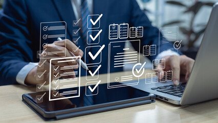 Businessman working on laptop with digital checklist and document approval icons, symbolizing...