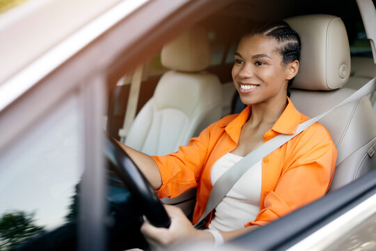 African American woman smiling while driving car with focus and confidence. Concept of safe driving, joy, and everyday lifestyle moments on the road