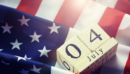 Cube shape calendar for July 04 on wooden table on usa flag background