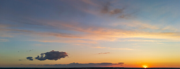 Breathtaking sunset skyline showcasing vibrant orange and purple hues. A single cloud drifts lazily...