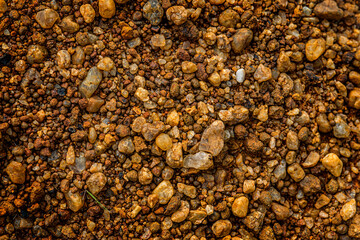 Dark gravel scattered on a dusty dirt road  textures , creating textural contrast, brown, grey