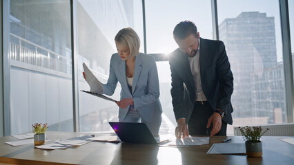 Multitasking colleagues reviewing documents city office. Team examining papers