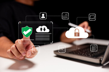 A person interacts with digital security icons, illustrating cloud storage and cybersecurity concepts, while using a laptop on a white surface.