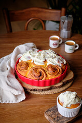 Cinnabon cinnamon rolls with pumpkin, nuts, caramel and mascarpone cream, covered with glaze. Rustic wooden table. Side view. Sweet homemade pastries, autumn pastries.