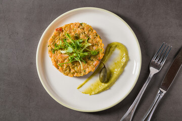 Baked vegetable patty with pea puree and microgreens garnish