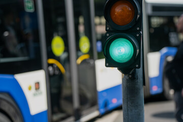 Green traffic light illuminated on signal post with city bus in background, directing safe urban transport flow and ensuring regulated movement of vehicles and pedestrians in daylight
