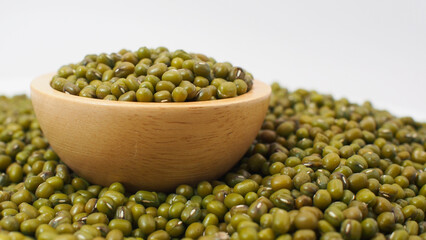 Raw Green Mung Beans in Wooden Bowl on Pile of Beans Background