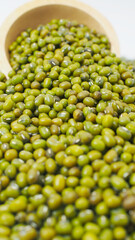 Close-up of mung beans spilling from a wooden bowl, symbolizing organic legumes, healthy food ingredients, and plant-based protein sources.