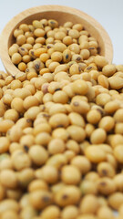 Soybeans spilling from wooden bowl on white background