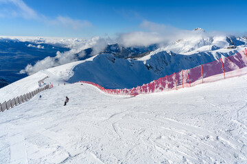 A red fence along a ski track with a view of the mountains.