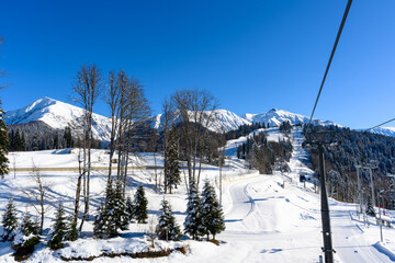 Winter landscape with a cable car, a mountain slope, and skiers
