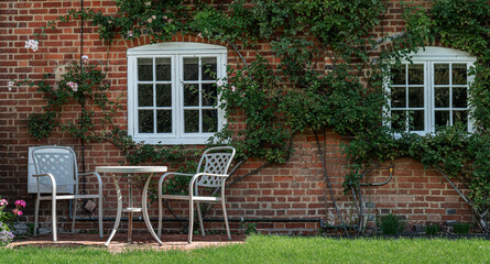 English garden with stylish table and chairs and climbing roses.